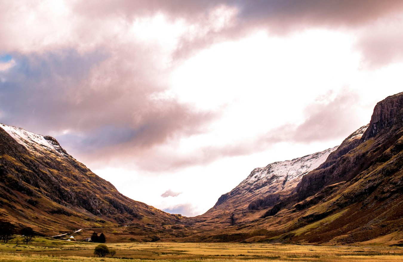 Breathtaking view of Glencoe Valley with snow-capped mountains and a dramatic sky.